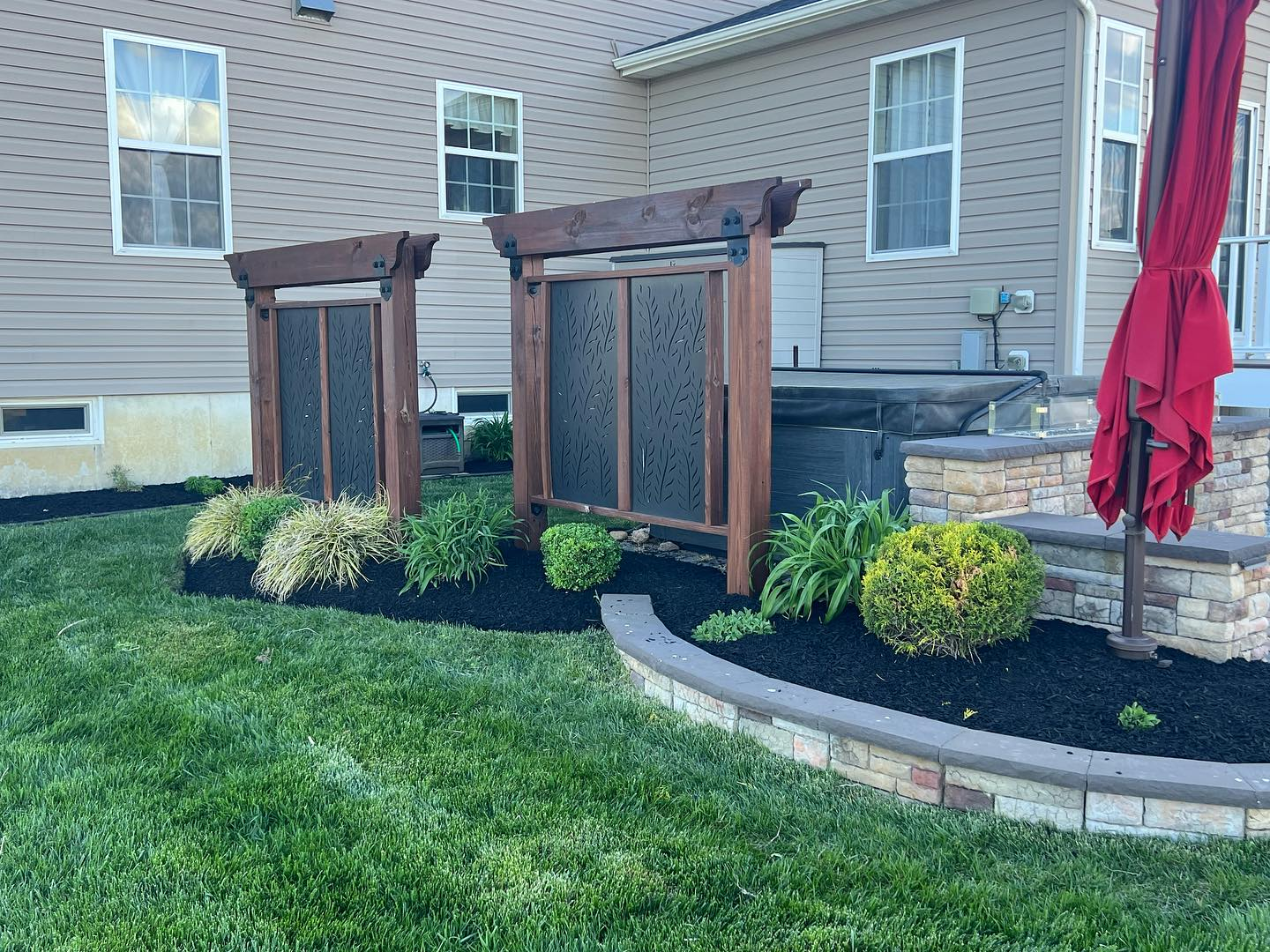 Backyard landscaping with privacy screens, mulch beds, and shrubs